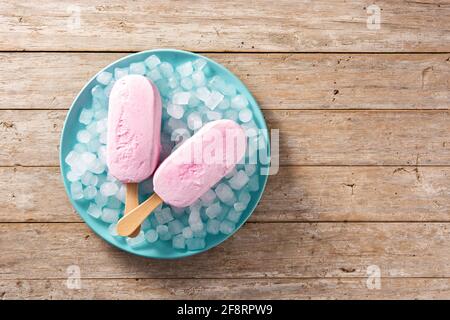 Strawberry popsicles and crushed ice on blue plate and wooden table Stock Photo