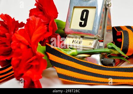 9 may card, vintage metal desk calendar with 9th May date and George ribbon and red carnations - Victory Day concept Stock Photo