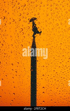 April fool's day with a silhouette of a clown on top of a tower on orange background with drops Stock Photo