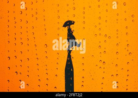 April fool's day with a silhouette of a clown on top of a tower on orange background with drops Stock Photo