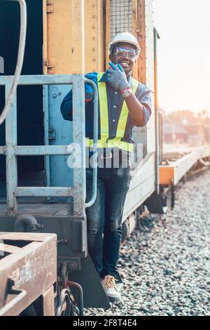 African man engineer holding radio communication or walkie talkie and hanging out of the  train Stock Photo