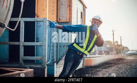 African man engineer holding radio communication or walkie talkie and hanging out of the  train Stock Photo