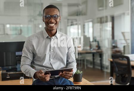 Smiling African businessman using a tablet at his office desk Stock Photo