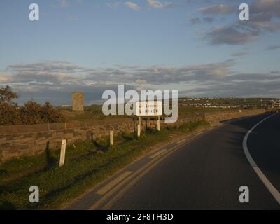 The empty road leading into Lahinch in county Clare Ireland. A signpost has for the town is seen with the letter A replacing the letter E in Lahinch. Stock Photo