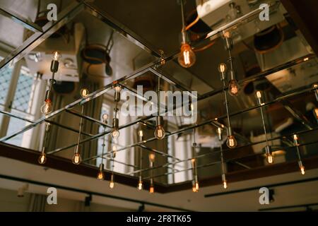 Mirrored ceiling with retro light bulbs in the interior of the restaurant. Stock Photo