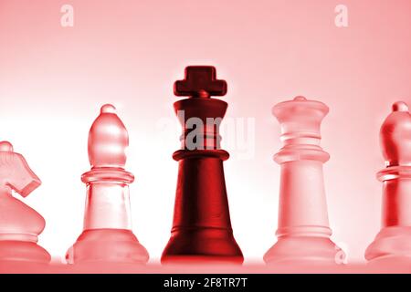 Deutschland. 11th Apr, 2021. Symbolic chess pieces of a chess game made of glass with a neutral background. Detail of some white figures and the black king with a red light mood from a slight frog's perspective. | usage worldwide Credit: dpa/Alamy Live News Stock Photo