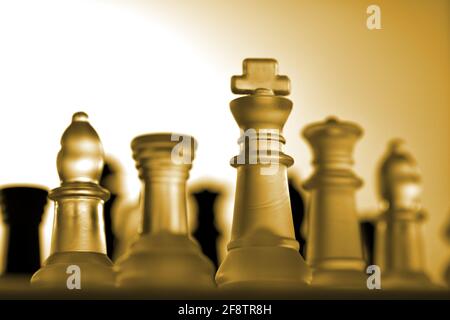 Deutschland. 11th Apr, 2021. Symbolic chess pieces of a chess game made of glass with a neutral background. Detail of some white figures with a golden/yellow light mood from a slight frog's perspective. There are some black figures in the background. | usage worldwide Credit: dpa/Alamy Live News Stock Photo