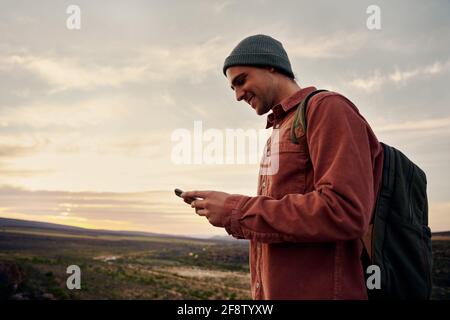Happy male hiker using smartphone on mountain top Stock Photo