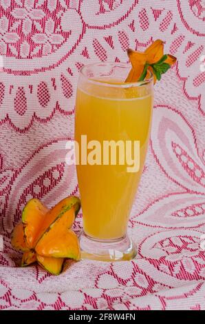 Whole Starfruit And Juice On Red And White Lacy Surface Stock Photo