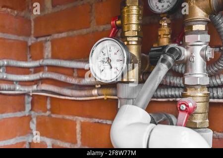 Pressure gauge on a pipe system with thermal insulation against the background of a heating unit at an industrial plant. Stock Photo