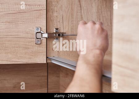 Srewdriver fixing kitchen cabinet door, close up Stock Photo