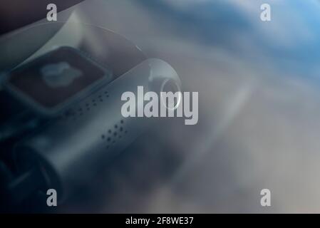 A modern car camera is attached to the inside of the windshield, under the mirror, in the shape of a tube. Stock Photo