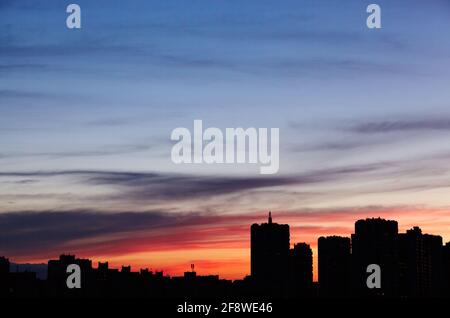 Colorful dramatic sky with clouds at sunset. City during warm sunset Stock Photo