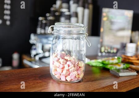 Jar with tasty mini marshmallows at bar counter in coffee shop. Blurred image, selective focus Stock Photo