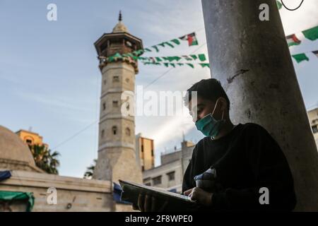 A Muslim young man reads a copy of the Holy Qur’an at the Medieval Al-Sayed Hashem Mosque in Gaza. Stock Photo