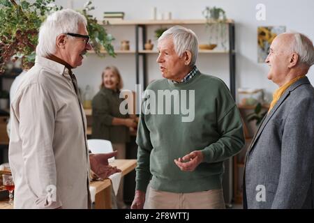 Group of senior men standing and discussing something during a meeting Stock Photo
