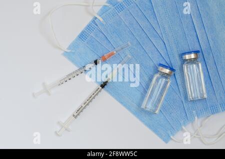 Creative ideas of diabetes concept. Insulin injection. Fighting with allergy. Top view of syringes with medical masks and vaccine vial glass bottles Stock Photo