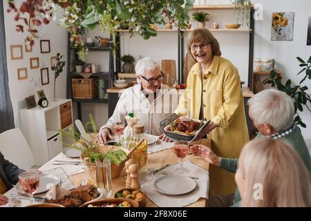 Group of old friends sitting at dining table and having dinner together during lunch time at home Stock Photo