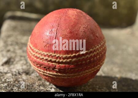 Close up of a red leather cricket ball on the sports field. Stock Photo