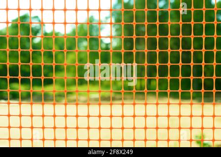 Plastic safety net for construction site. Construction mesh on winter snow background. Stock Photo