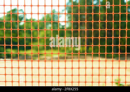 Plastic safety net for construction site. Construction mesh on winter snow background. Stock Photo
