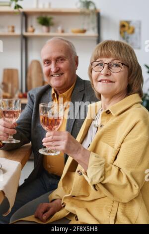 Portrait of happy senior couple smiling at camera while they drinking wine during dinner at the restaurant Stock Photo