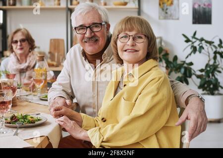 Portrait of happy senior couple smiling at camera sitting at dining table during dinner at home Stock Photo