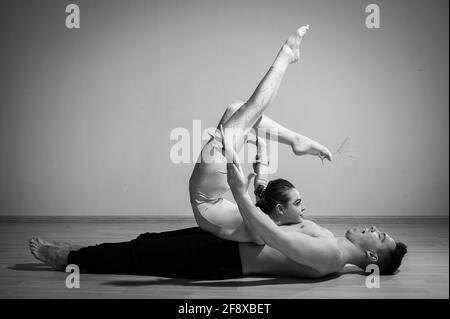 Heavy circus pose. A young man holds a flexible woman. Two acrobats or ballet dancers posing on a white background. A pair of gymnasts perform art. Stock Photo