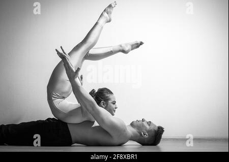 Heavy circus pose. A young man holds a flexible woman. Two acrobats or ballet dancers posing on a white background. A pair of gymnasts perform art. Stock Photo