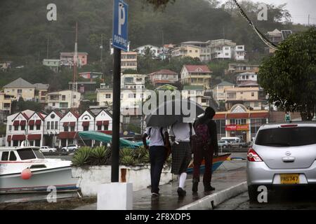 St George Grenada School children walking along the Carenage in the rain Stock Photo