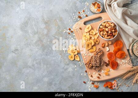 Dried bananas, apricots, raisins and various types of nuts on a gray background. Top view with copy space. Healthy, natural sweets. Stock Photo