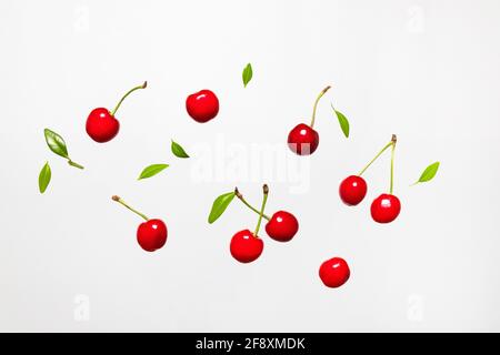 Ripe cherry berry with green leaves levitating on white background. Berry summer background. Flat lay, top view, copy space Stock Photo