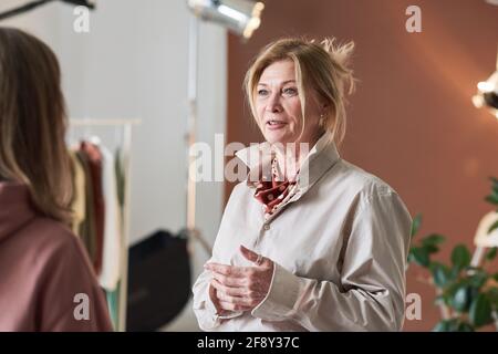 Mature businesswoman discussing working moments together with her colleague at office Stock Photo
