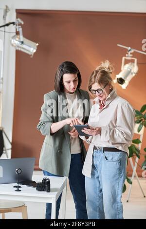 Businesswoman using digital tablet together with her colleague while they standing at office Stock Photo