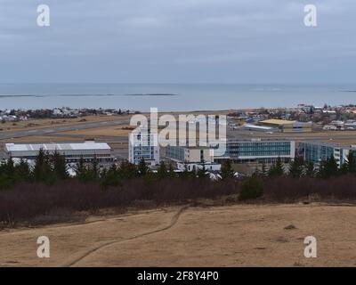 Aerial view of Reykjavik domestic airtport with runway and terminal building viewed from Perlan on Öskjuhlíð hill on cloudy winter day. Stock Photo