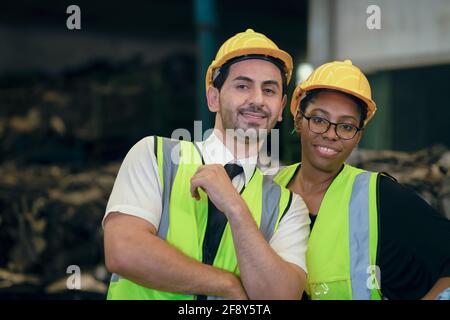 Couple friend Team Worker mix race  enjoy working in heavy factory standing together happy smiling portrait shot looking camera Stock Photo