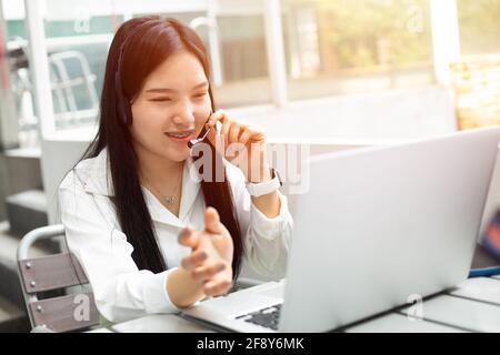 Business women telemarketing video calling client phone call with headset, female working outdoor happy smile Stock Photo