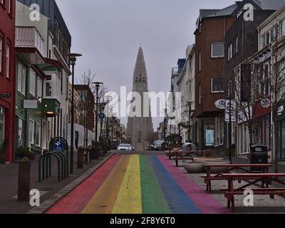 View of empty rainbow street in Reykjavik city center, dedicated to the annual Reykjavik Pride Gay Festival, with Hallgrímskirkja church on cloudy day.
