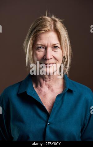 Close-up of senior blonde woman in blouse looking at camera isolated on black background Stock Photo