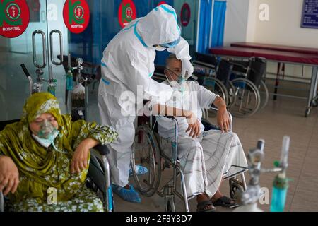 Dhaka, Bangladesh. 12th Apr, 2021. A medical worker wearing a personal protective equipment suite (PPE) adjusts the oxygen mask for an intubated COVID-19 patient at Kurmitola General Hospital in Dhaka.Death toll from the coronavirus infection has surpassed the grim 10,000 mark in Bangladesh as 94 more people have died of the deadly virus in the past 24 hours. Credit: Sultan Mahmud Mukut/SOPA Images/ZUMA Wire/Ģ����ý Live News Stock Photo