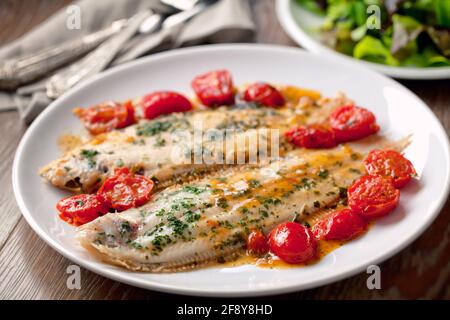 Sole with cherry tomatoes on a plate. High quality photo. Stock Photo
