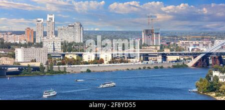 Panoramic cityscape of the Dnipro with cruising pleasure boats against the background of the Kyiv embankment, bright beautiful sky and city buildings. Stock Photo