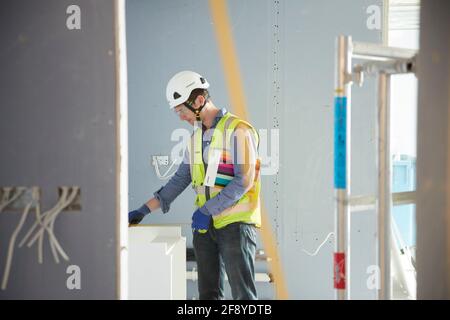 site manager measures basin unit on building site Stock Photo
