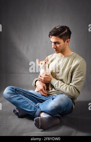 Man holding and kissing muzzle cute Devon rex cat Stock Photo