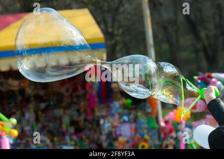 Bright big soap balls in the park. Children inflate soap bubbles and beautiful foam balls hang in the air. Stock Photo