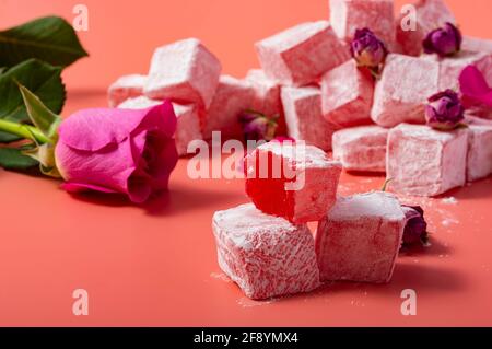 Levitating rose flavoured pink Turkish delight with flower petals and dry rosebuds on pink background Stock Photo