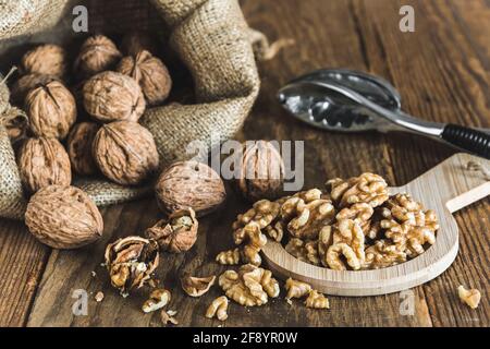Whole and peeled walnuts on a rustic wooden table, focus on the walnut kernels Stock Photo