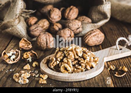 Whole and peeled walnuts on a rustic wooden table, focus on the walnut kernels Stock Photo