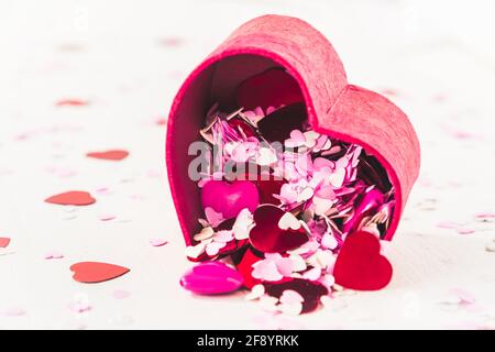 Little red, pink and white hearts for decoration pour out of a heart-shaped little box. With copy space. Stock Photo