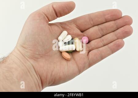 A handful of pills in a man's hand on a white background. Stock Photo